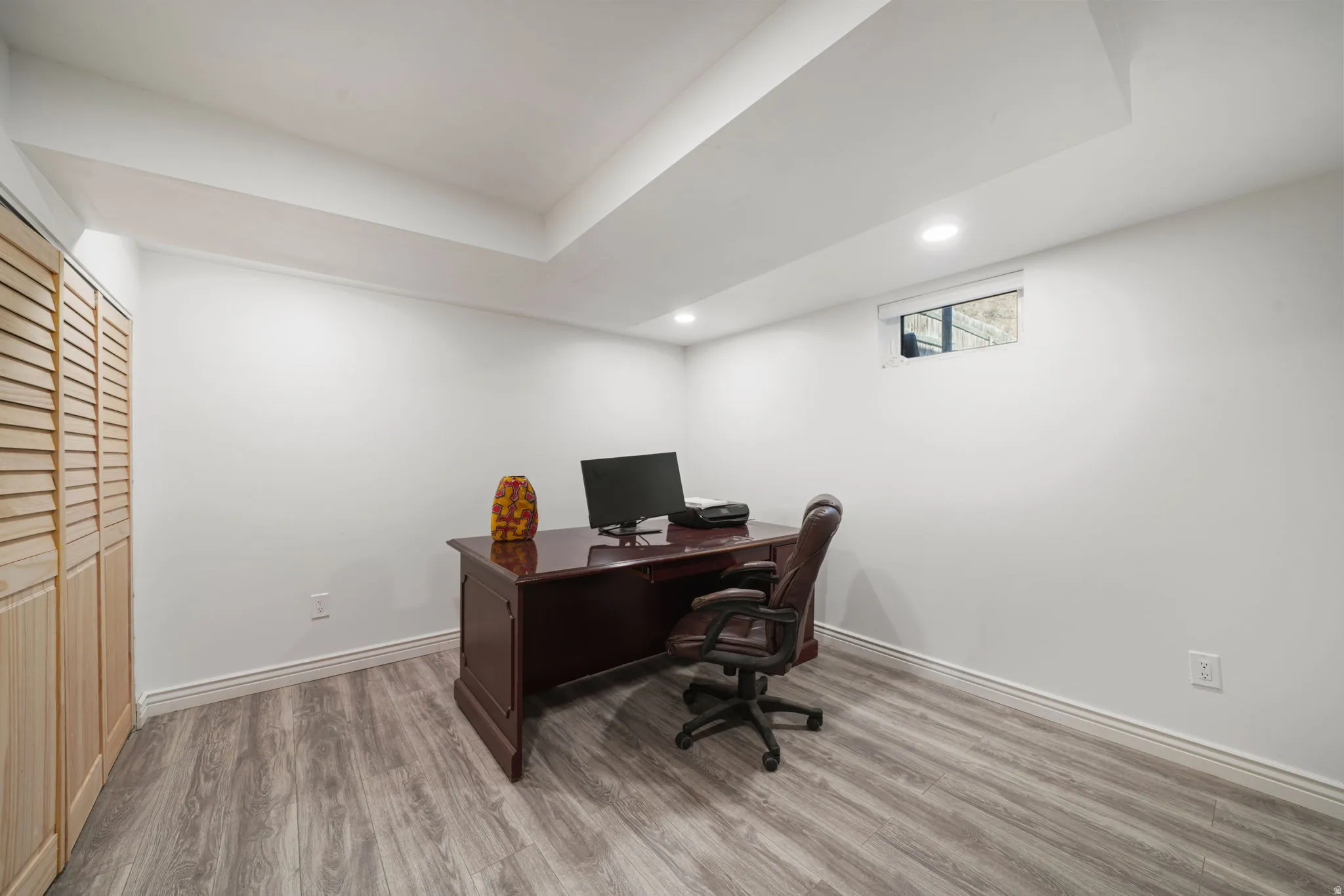 Recessed lighting, wood-finish flooring, white walls, and a wood-slat bi-fold closet