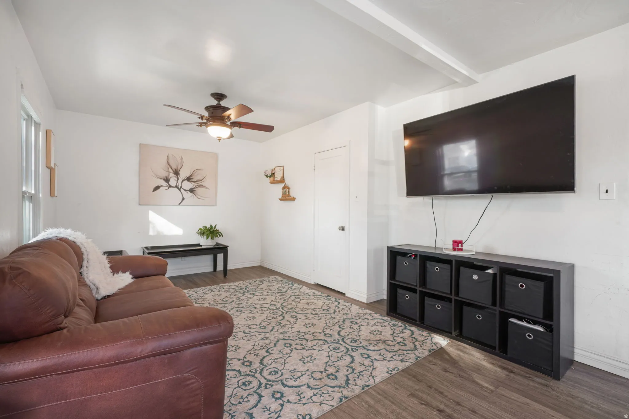 Wood-finish flooring throughout, bright white walls, and a ceiling fan with integrated lighting