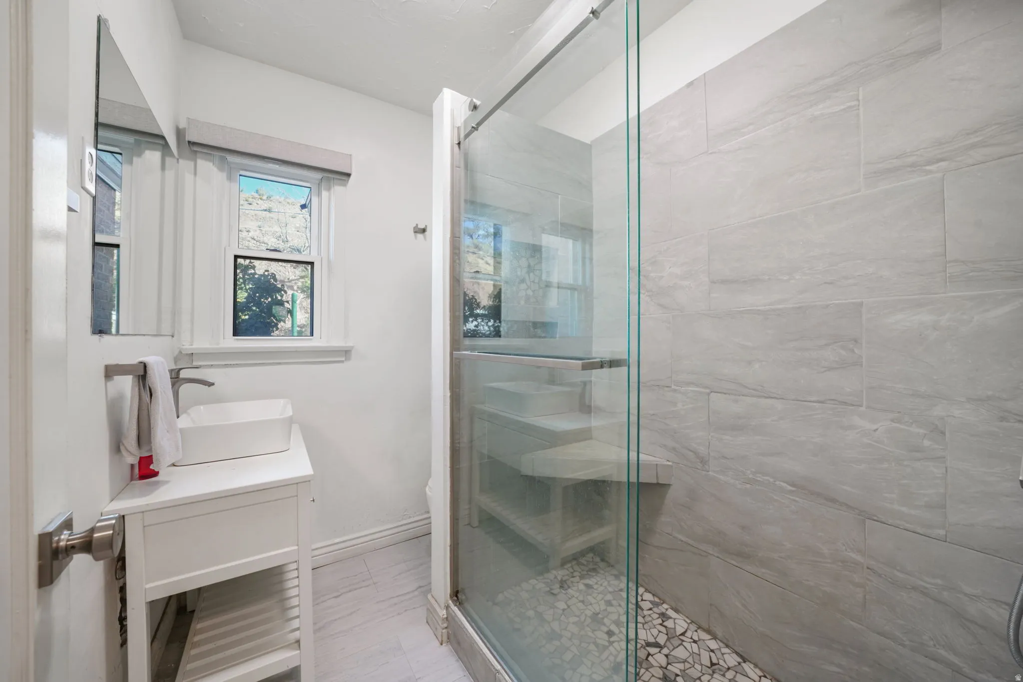 Walk-in shower with clear glass enclosure and stone tile walls