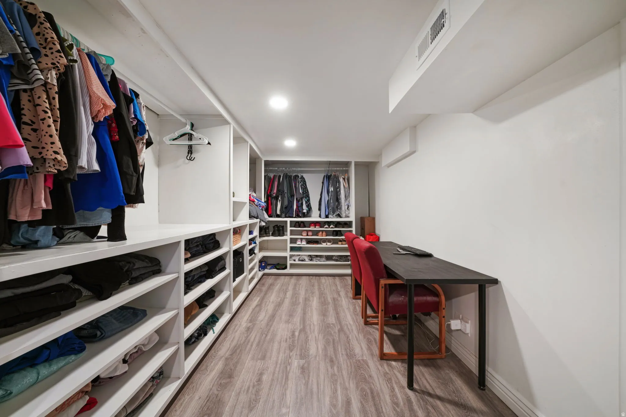 Custom built-in shelving, recessed ceiling lighting, wood-finish flooring, and a dedicated desk area