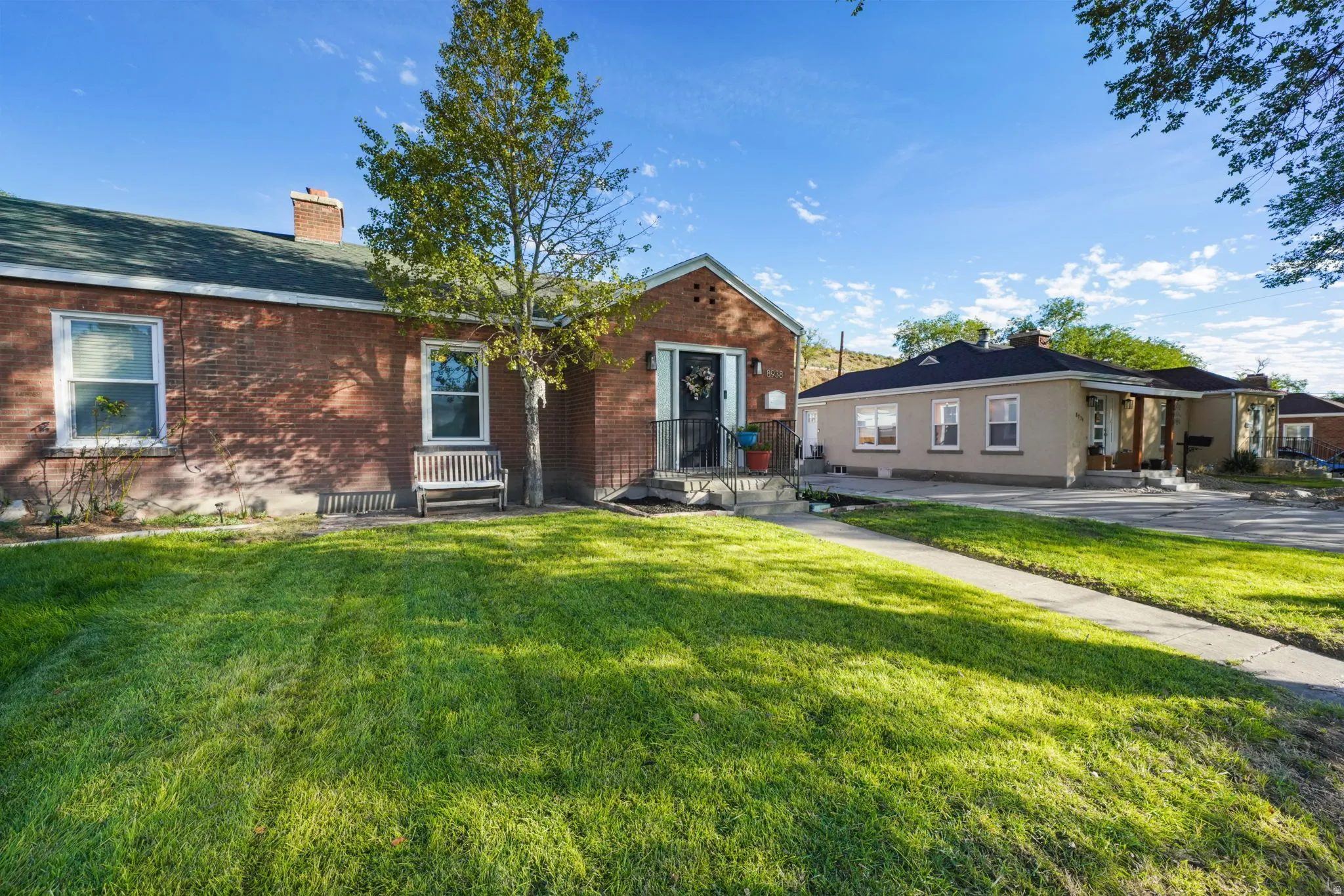 Brick exterior with a gabled entry, concrete walkway, and established lawn