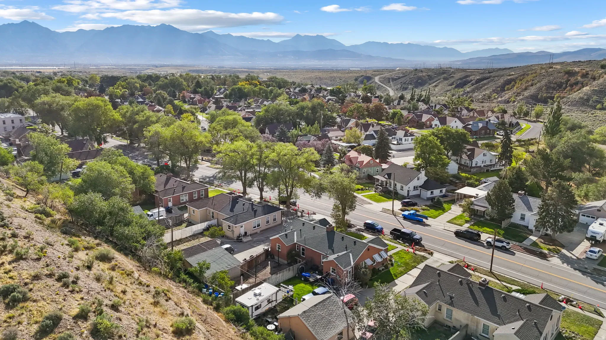 Residential neighborhood with mature trees, paved streets, and a mountainous backdrop