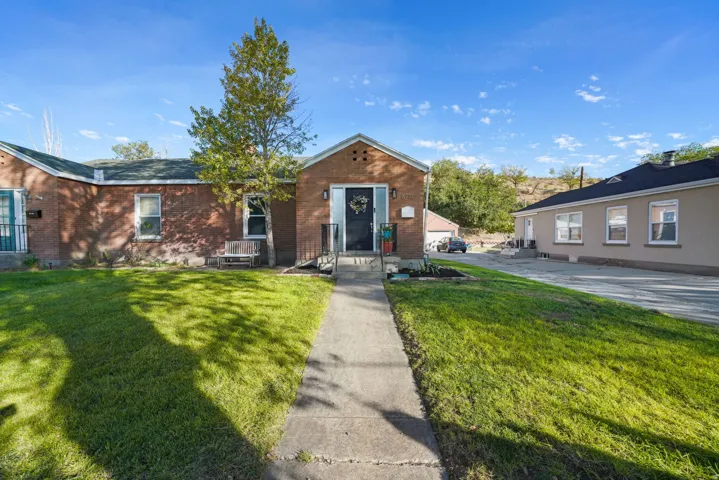 Brick exterior with manicured lawn and mature landscaping, featuring a concrete walkway leading to the front entrance