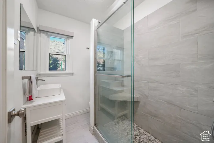 Walk-in shower with clear glass enclosure and stone tile walls