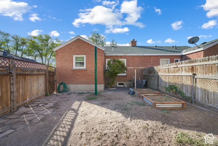 Enclosed backyard featuring a wood fence, flagstone path, and raised garden beds