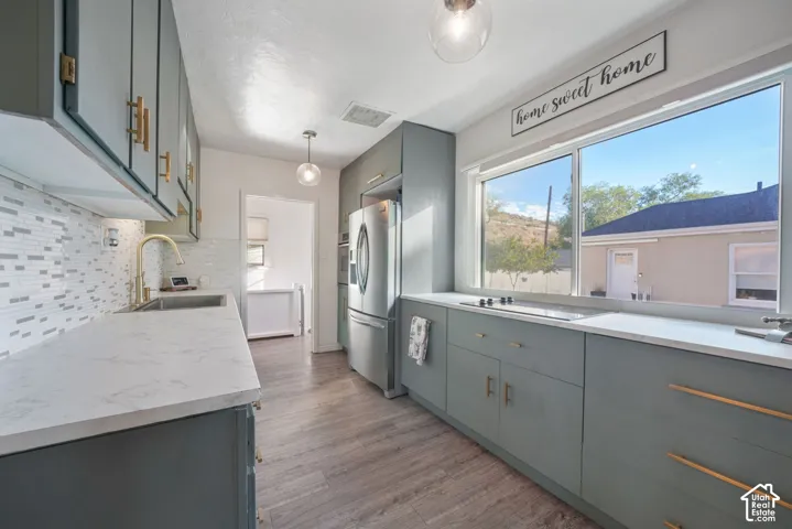 Kitchen featuring wood-finish flooring, light-toned cabinetry with gold-tone hardware, and a white countertop