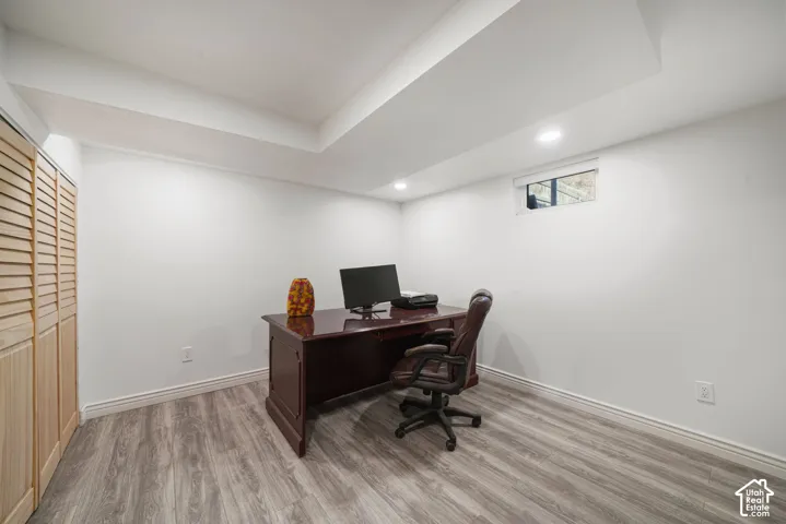 Recessed lighting, wood-finish flooring, white walls, and a wood-slat bi-fold closet