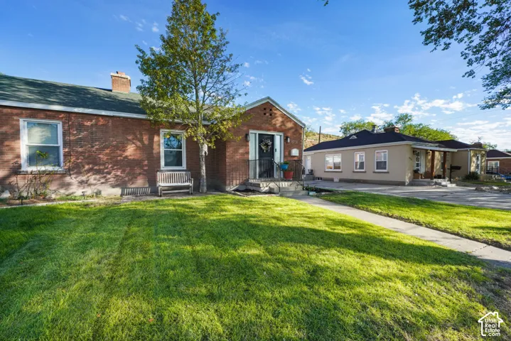 Brick exterior with a gabled entry, concrete walkway, and established lawn