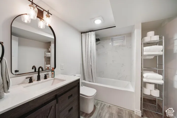 Vanity with quartz countertop and undermount sink, dark wood-finish cabinetry, matte black fixtures, and wood-finish flooring