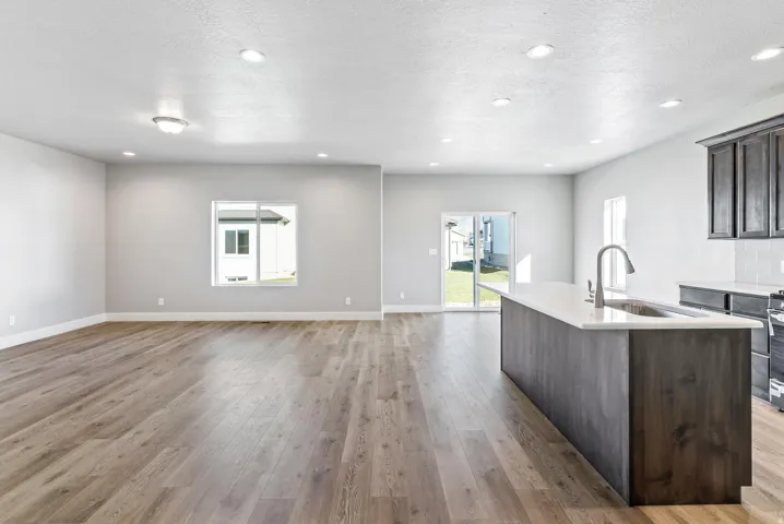 Open-concept living space featuring wood-finish flooring, recessed lighting, and a kitchen island with an undermount sink