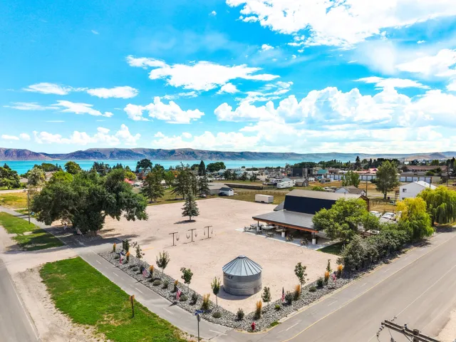 Expansive lot featuring a large commercial building, a detached silo structure, mature trees, and a landscaped rock garden with ornamental grasses