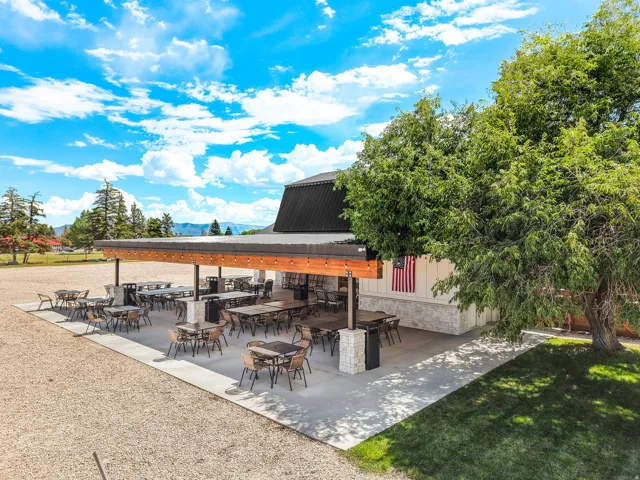 Expansive outdoor patio with a covered section, string lighting, and stone-clad support pillars