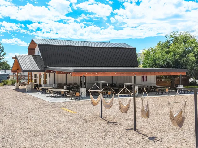 Barn-style exterior featuring a dark metal roof, white vertical siding, and a covered patio with exposed wood beams