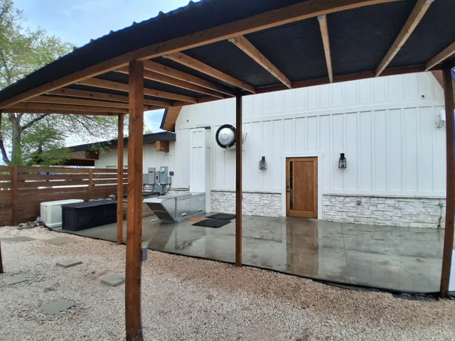 Covered patio with wood beams, metal roof, and concrete flooring