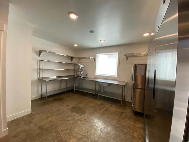 Stainless steel shelving, concrete flooring, recessed lighting, and a large window