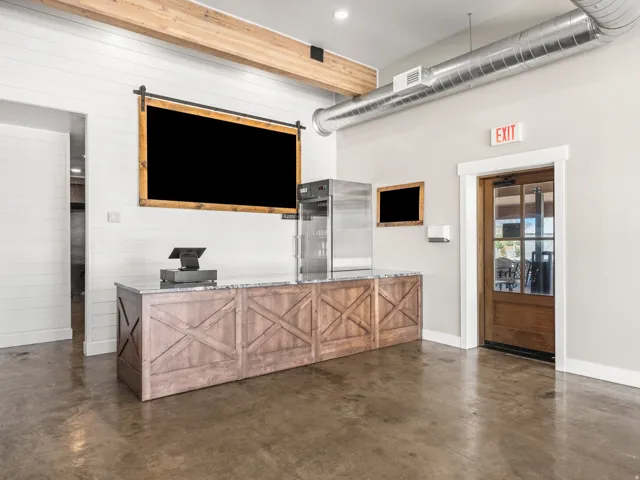 Polished concrete flooring, barn-style cabinetry with stone countertop, exposed wood beam ceiling detail, and visible galvanized ductwork