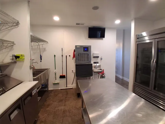 Stainless steel work surfaces, commercial-grade refrigeration, stainless steel sink, and overhead wire shelving