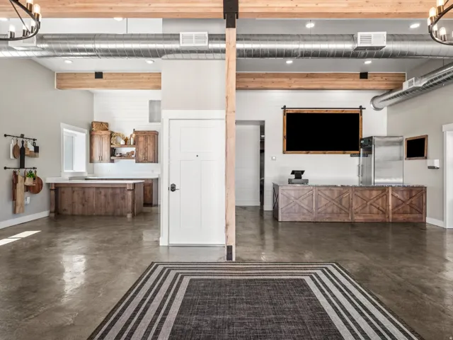 Exposed wood beams, polished concrete flooring, industrial-style exposed ductwork, wood-finish cabinetry, and a solid white door