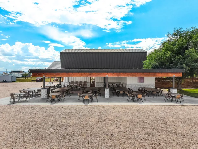 Expansive covered patio with a dark metal roof, wood-beam accents, and concrete flooring