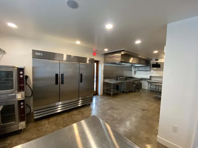 Commercial-grade kitchen featuring stainless steel appliances, multiple ovens, large refrigeration units, and expansive work surfaces
