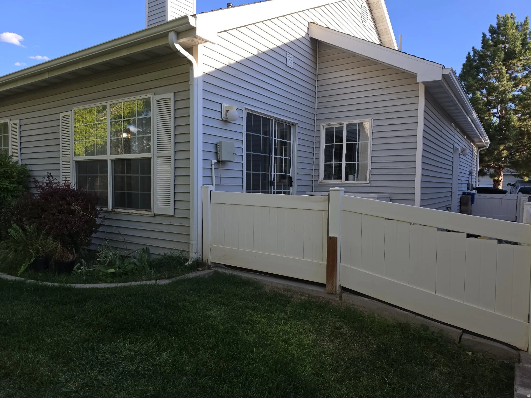 Vinyl siding exterior with a sliding glass door and a white privacy fence