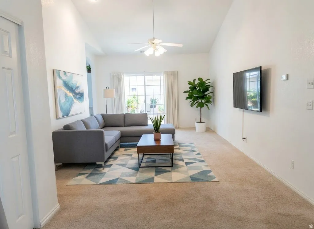 Vaulted ceilings with a ceiling fan, carpeted flooring, and a wall-mounted television