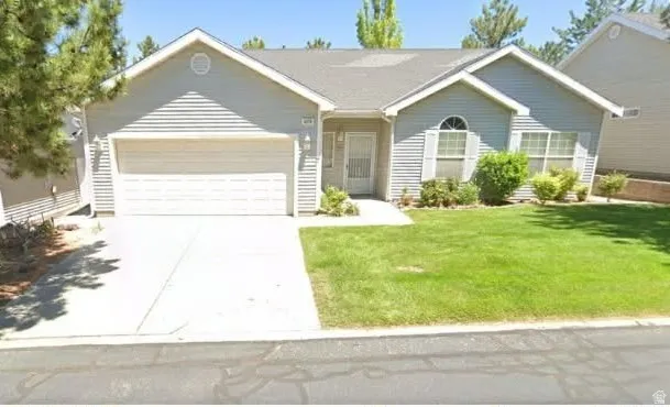 Single-story residence featuring light-colored siding, an attached garage, and a concrete driveway