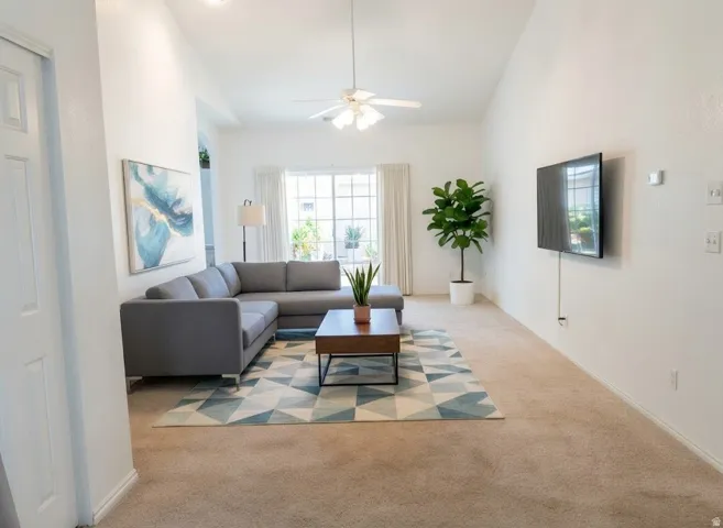 Vaulted ceilings with a ceiling fan, carpeted flooring, and a wall-mounted television