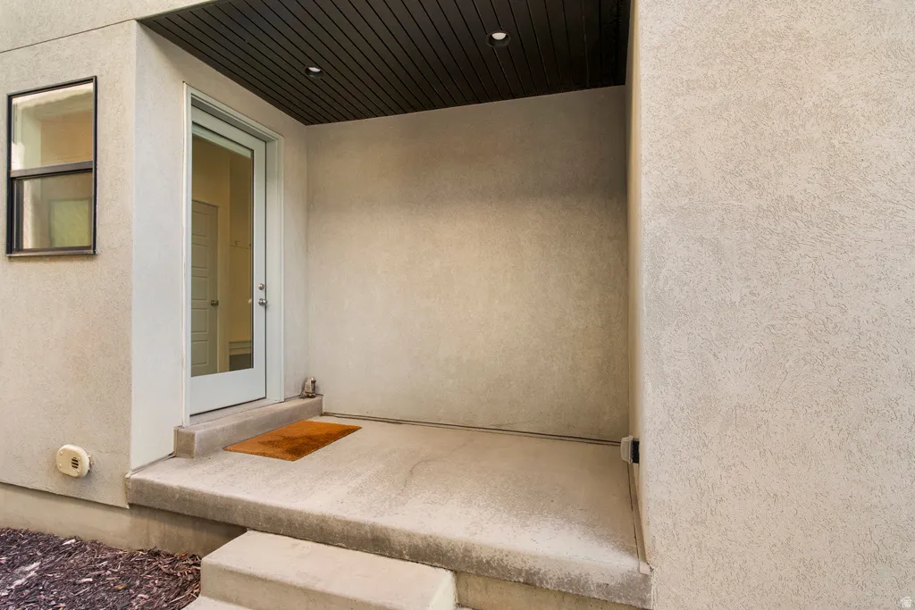 Covered entryway featuring a full-light entry door, recessed ceiling lighting, and stucco exterior finish