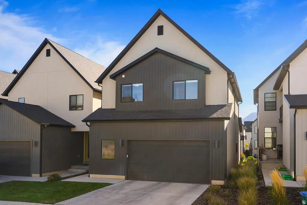 Contemporary facade with board and batten siding, attached garage, and light stucco accents