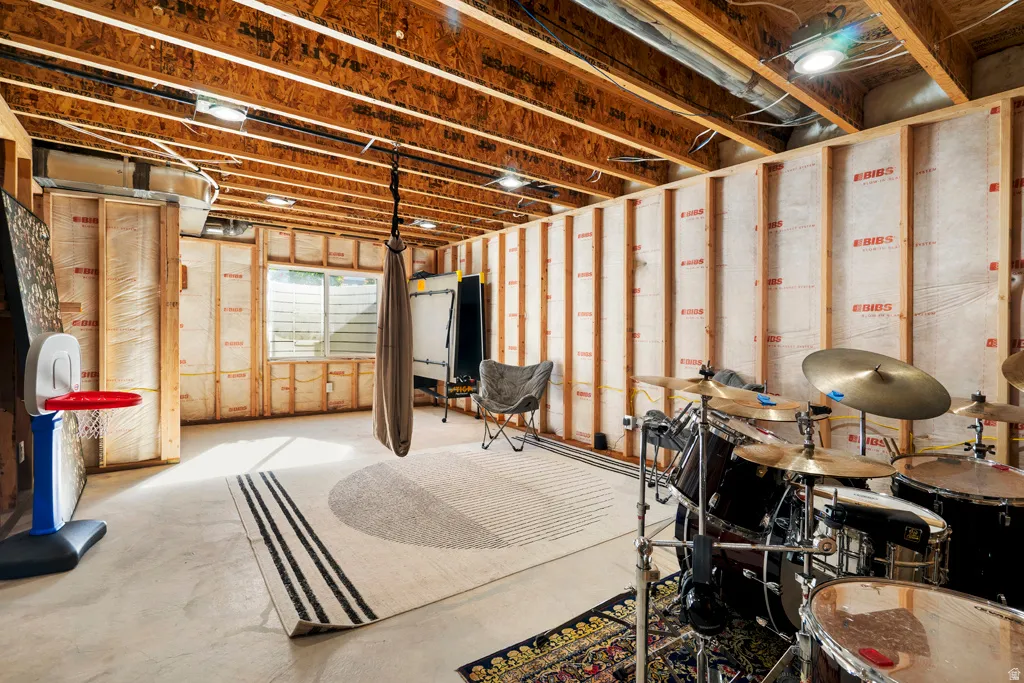 Unfinished basement space featuring exposed wood joists, framed walls with insulation, concrete flooring, recessed lighting, and a visible window