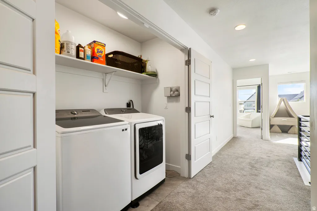 Dedicated laundry area featuring a white washer and dryer, integrated shelving, and a utility sink