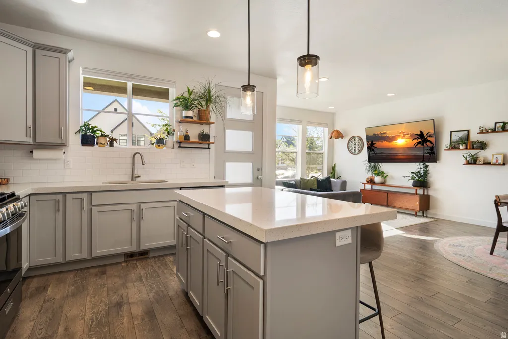 Kitchen featuring light gray cabinetry, white subway tile backsplash, and a large center island with a light-toned countertop