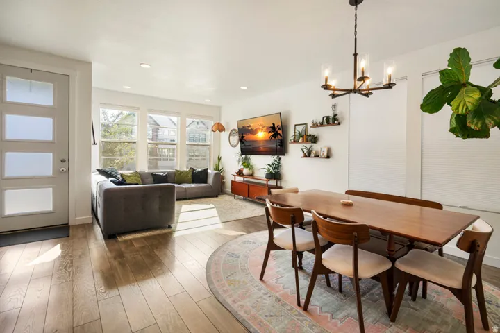 Open-concept living area with wood-finish flooring, a wall of windows, and recessed lighting