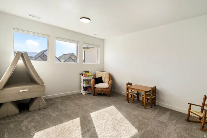 Recessed ceiling lighting, three expansive windows, wall-to-wall carpeting, and bright white walls