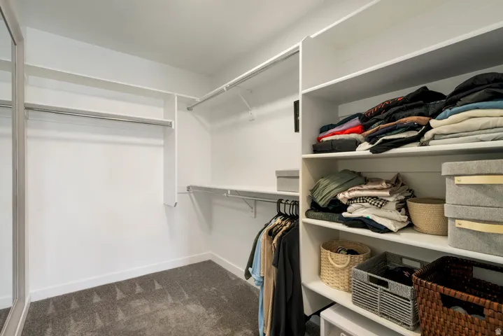 Walk-in closet with built-in shelving, multiple hanging rods, and carpet flooring