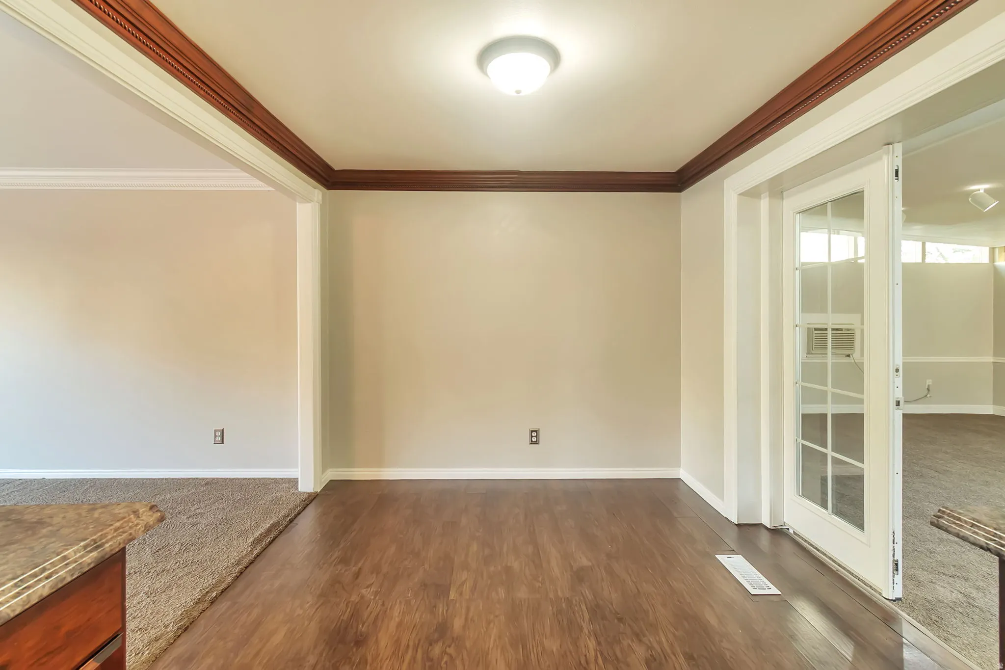 Wood-finish flooring, crown molding, white trim, recessed lighting, and French doors