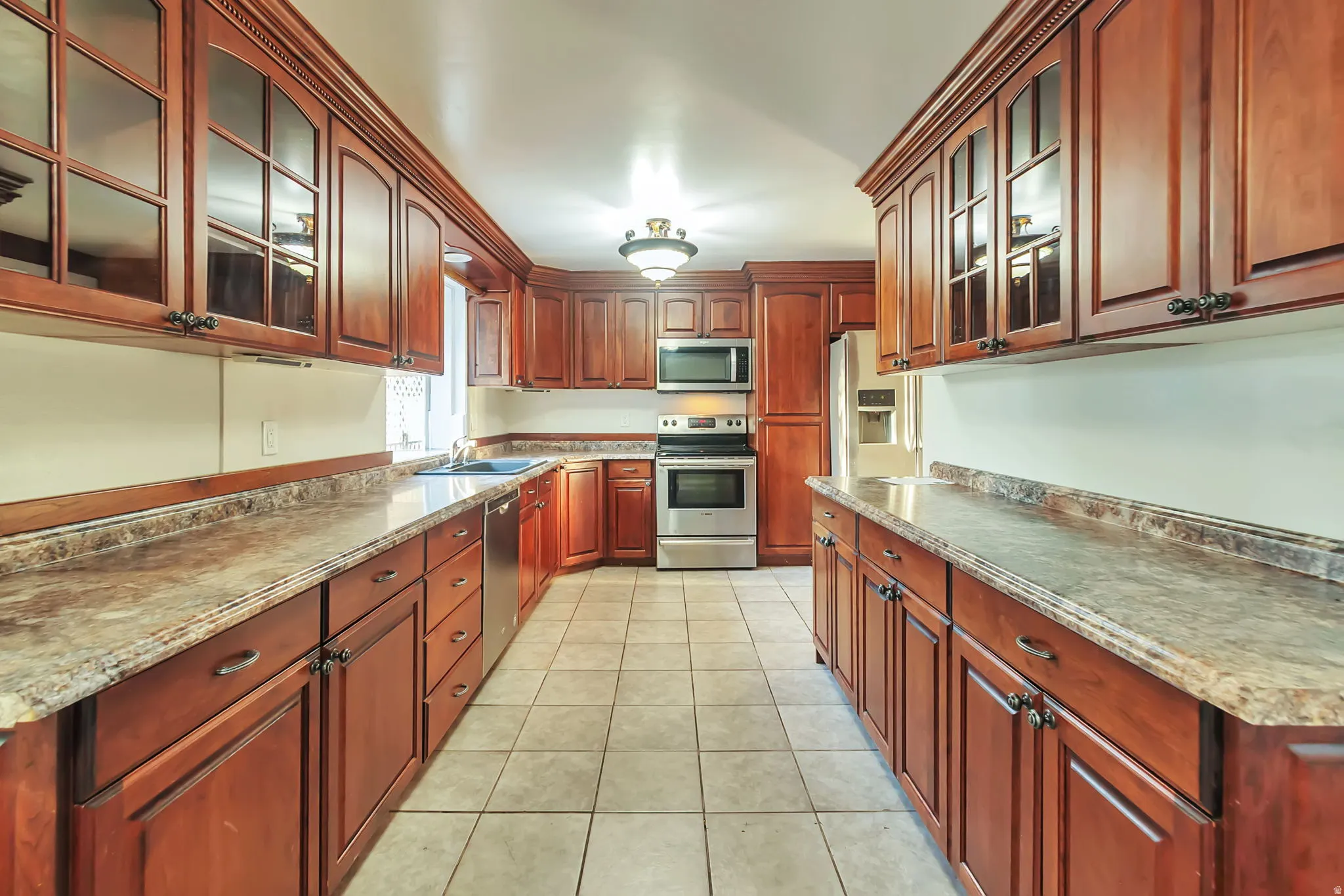 Kitchen with rich wood cabinetry, stainless steel appliances, and tiled flooring
