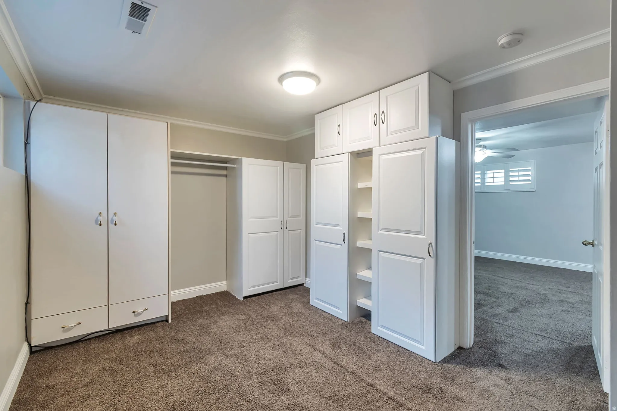 Built-in white cabinetry, open shelving, and a hanging clothes rod for storage