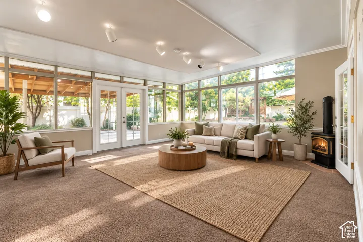 Spacious sunroom/family room featuring extensive window-lines, French doors, track lighting, and a standalone fireplace