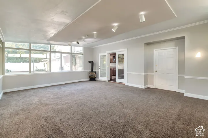Bright family/sun room with a wood-burning stove, large pane windows, recessed ceiling lighting, and French doors
