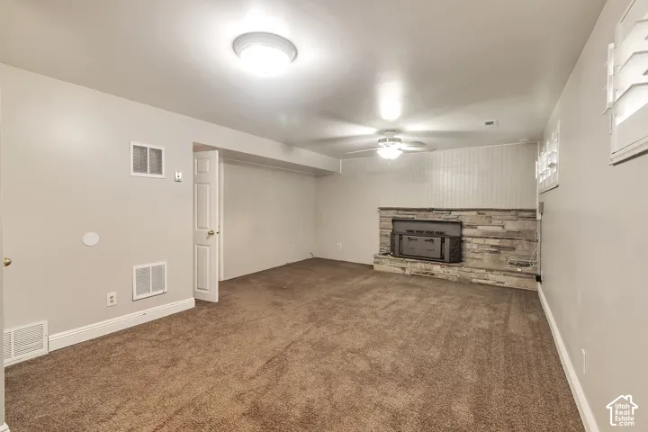 Carpeted family room featuring a stone-fireplace and hearth