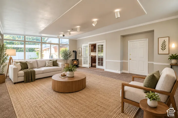 Expansive sunroom/living room with large windows, wood-burning stove, recessed lighting, and crown molding