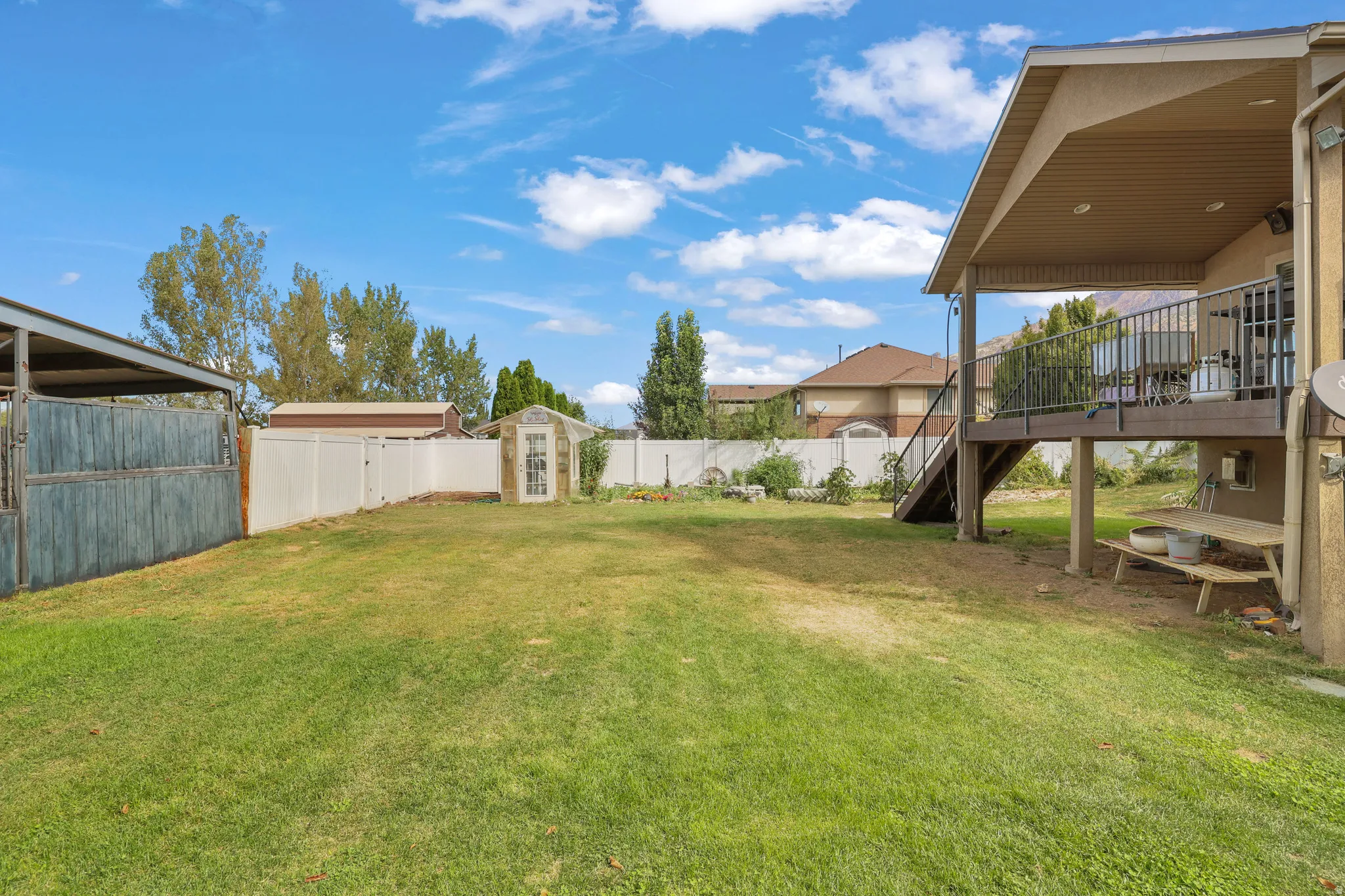 Expansive backyard featuring a covered upper deck, ground-level patio space, enclosed storage shed, and a privacy fence