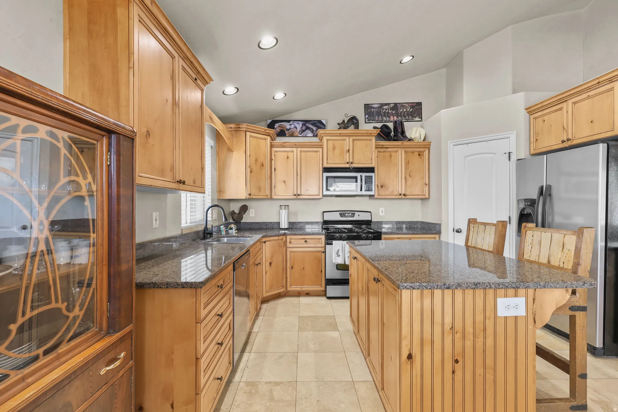 Kitchen featuring wood cabinetry, an island with countertop seating, stainless steel appliances, recessed lighting, and tile flooring