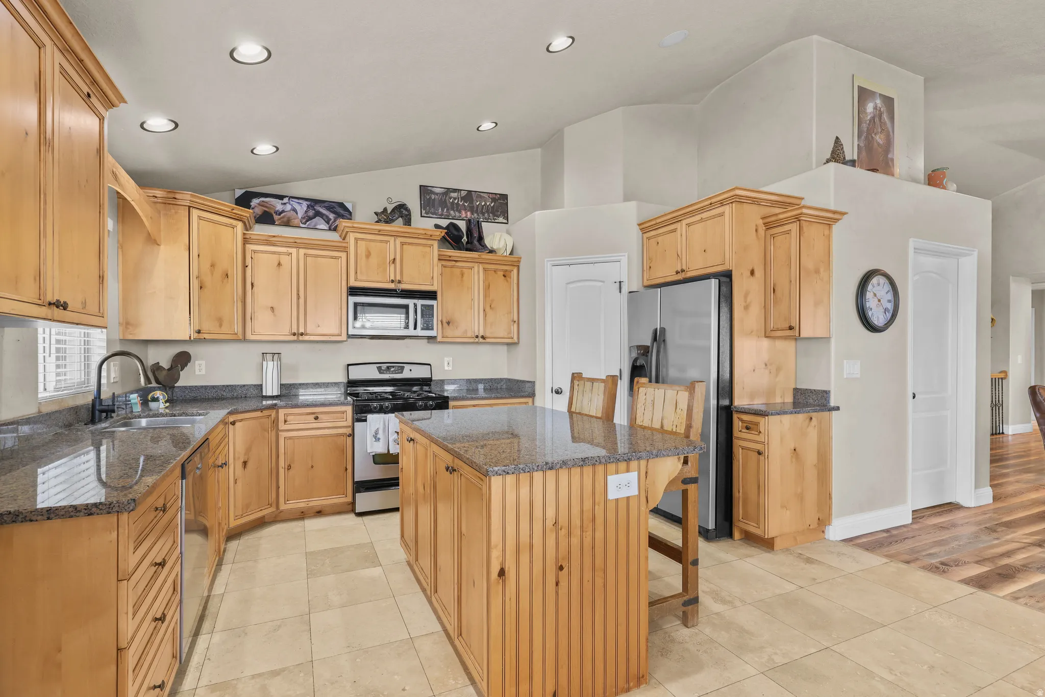 Kitchen featuring wood cabinetry, stainless steel appliances, an island with seating, and tile flooring