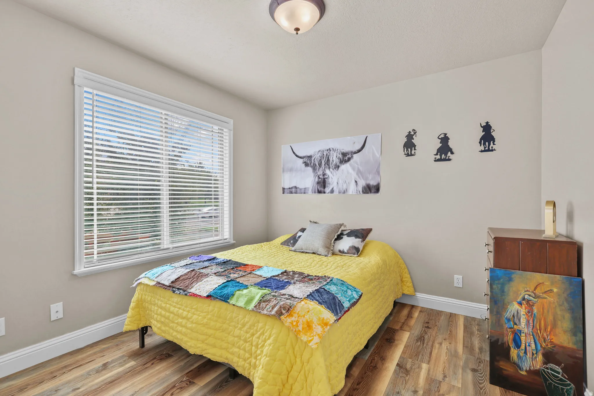 Wood-finish flooring, neutral wall color, white trim, and a window with blinds