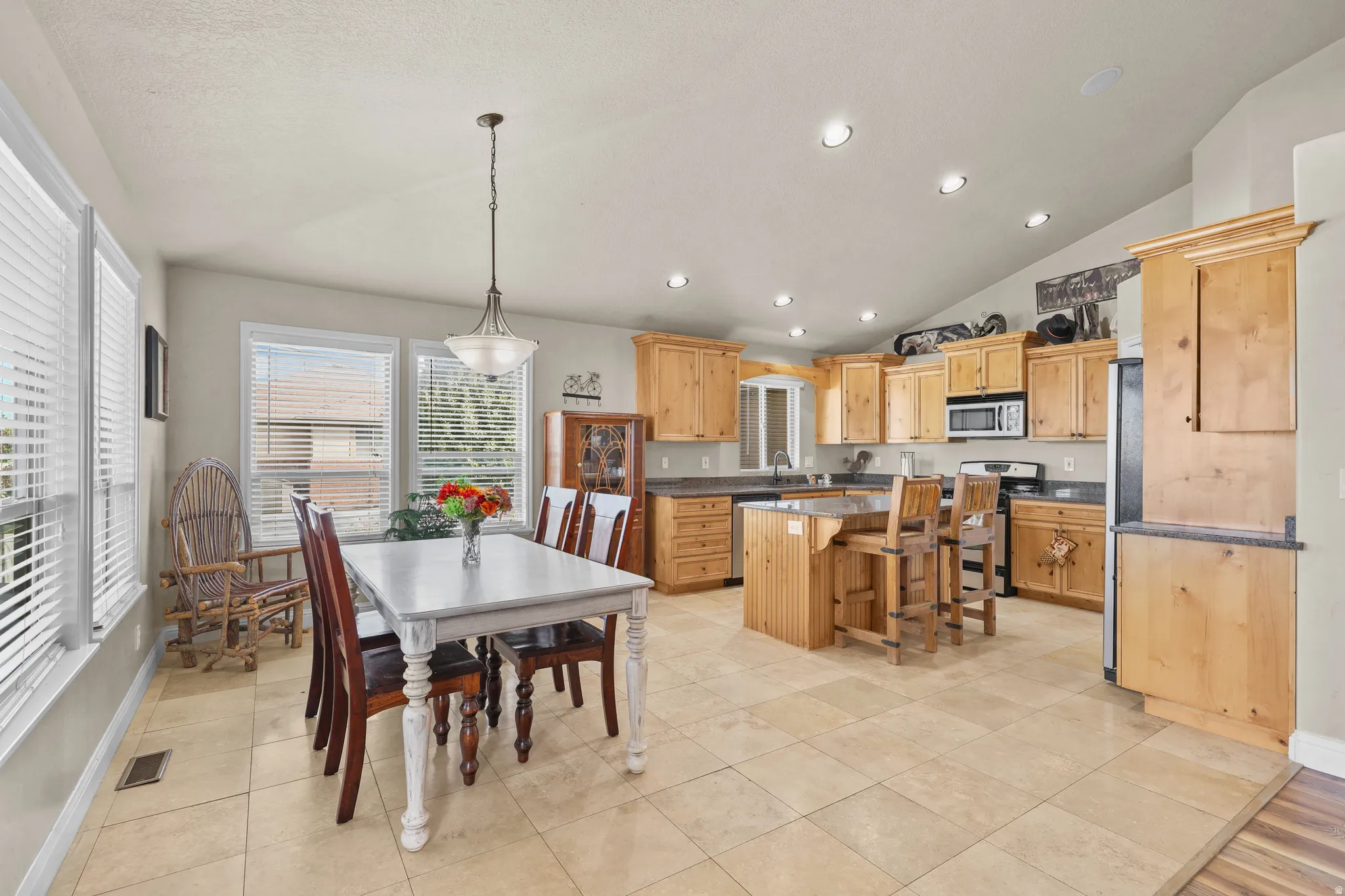 Open-concept kitchen and dining area featuring light-toned cabinetry, stainless steel appliances, and a central island with seating