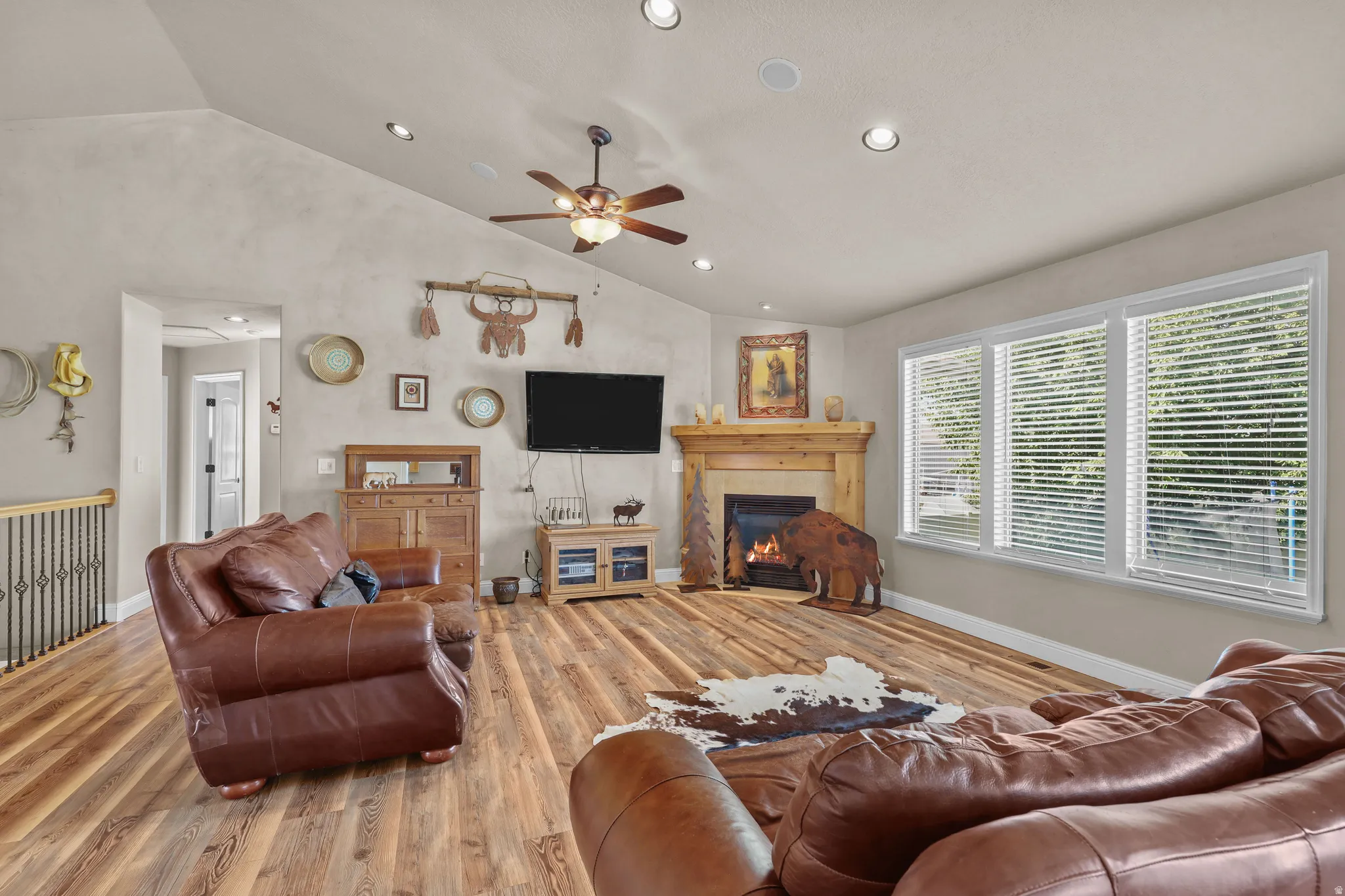 Vaulted ceiling with recessed lighting, wood-finish flooring, and a fireplace with a wood mantel