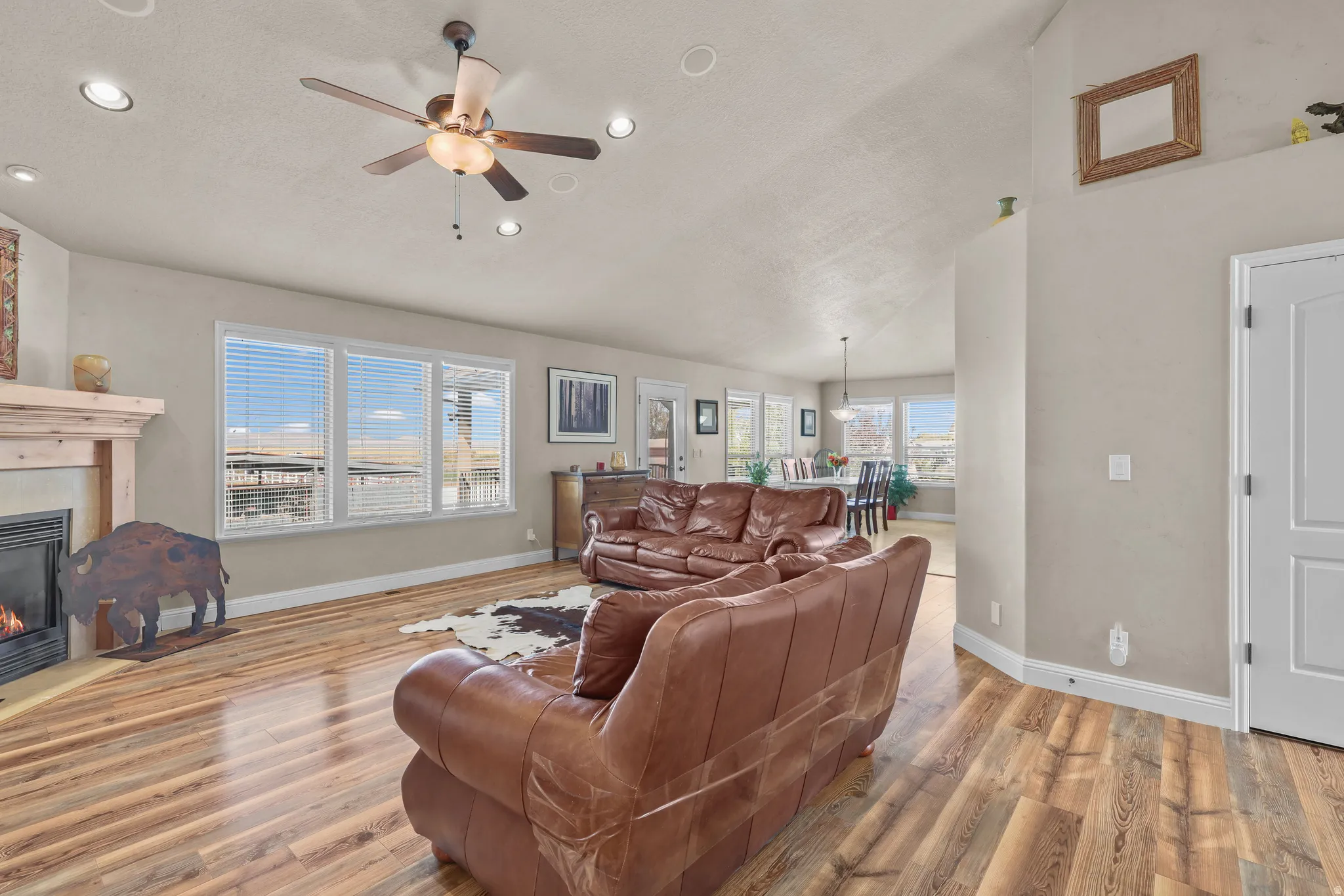 Spacious living area featuring wood-finish flooring, a fireplace with a wood mantle, and multiple windows providing ample natural light